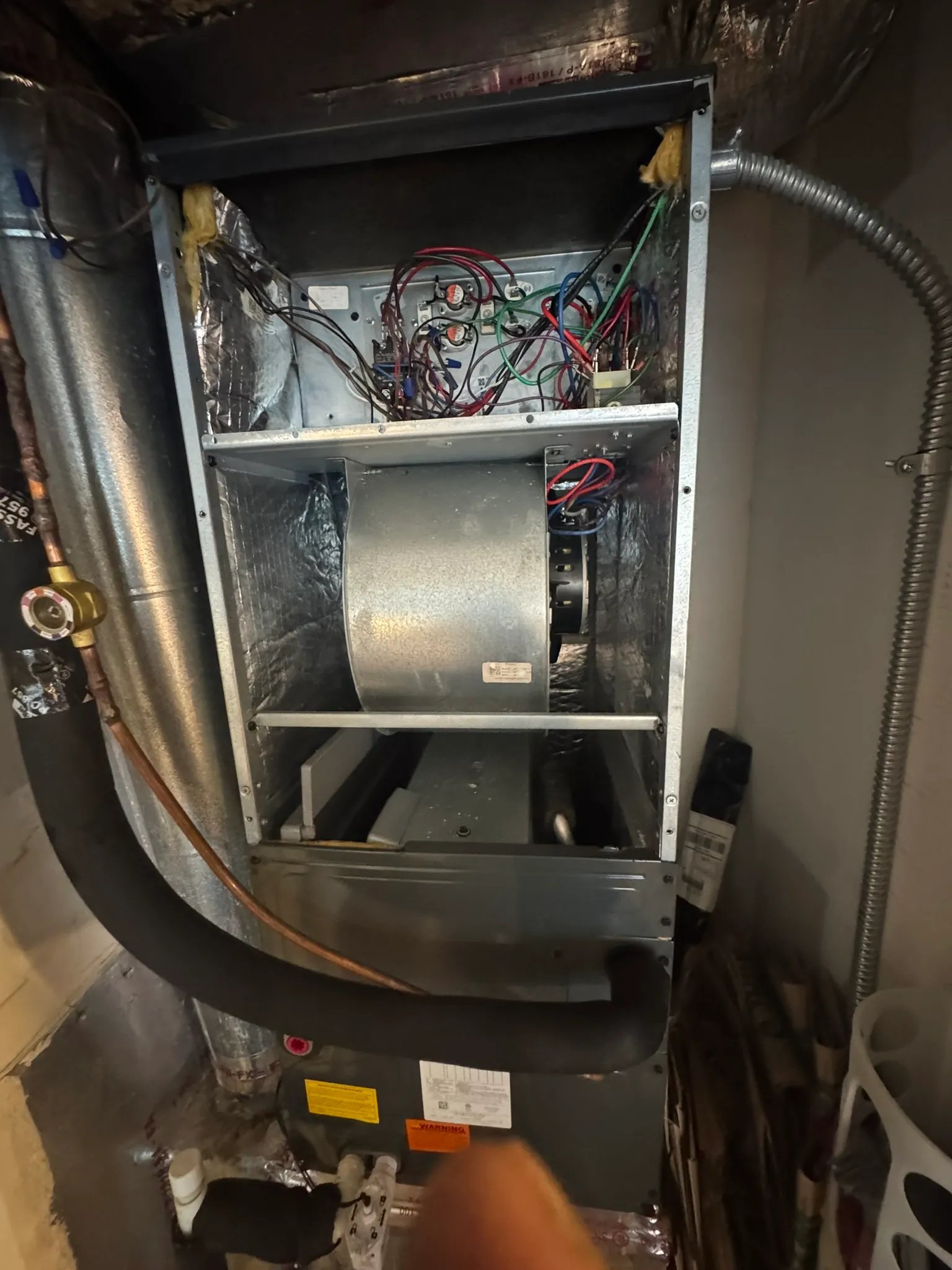 Air handler with panels off: blower wheel below, heat-strip wiring above