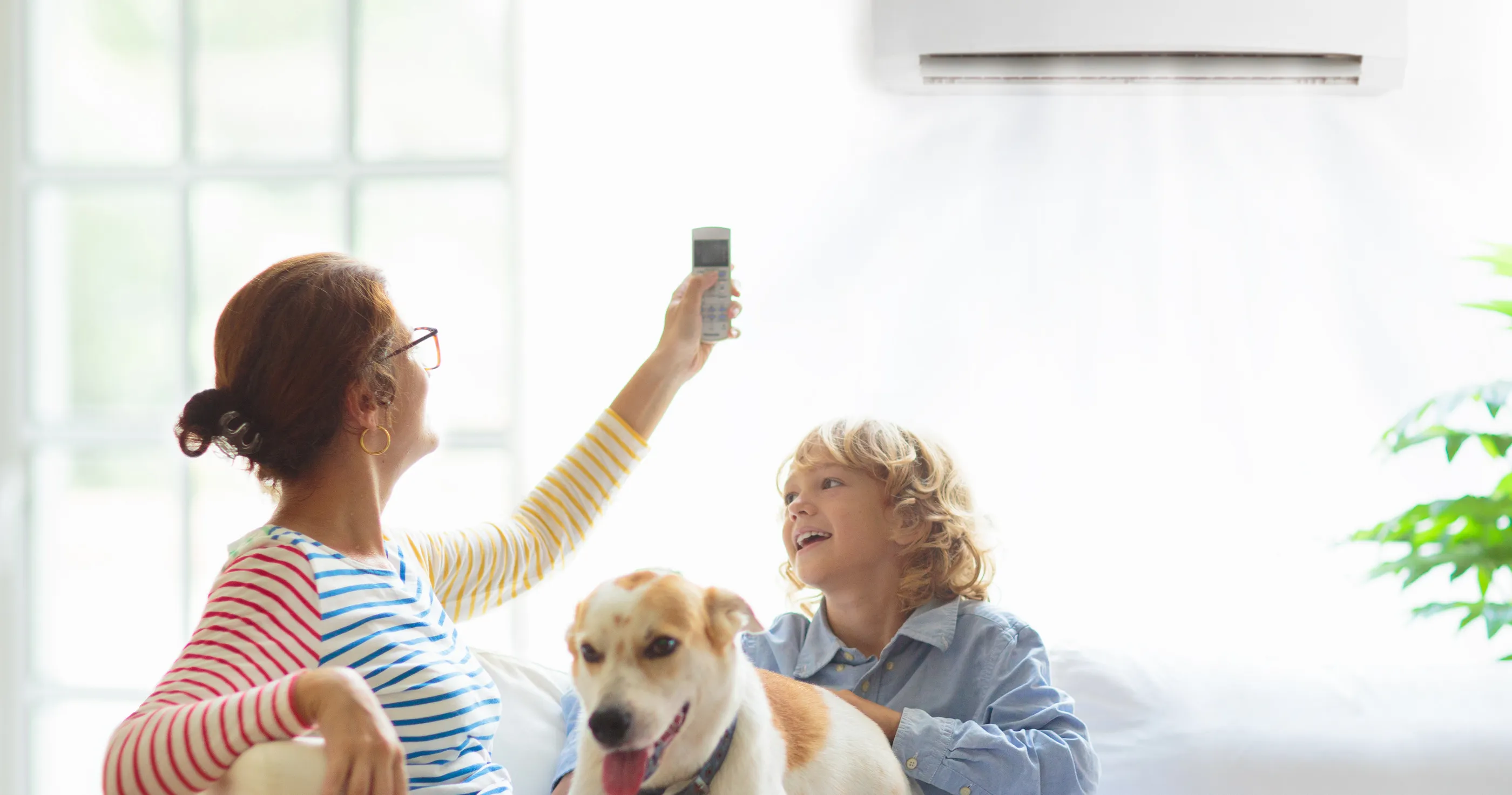 A wall-mounted mini-split cooling a Florida living room while a family sits on the sofa