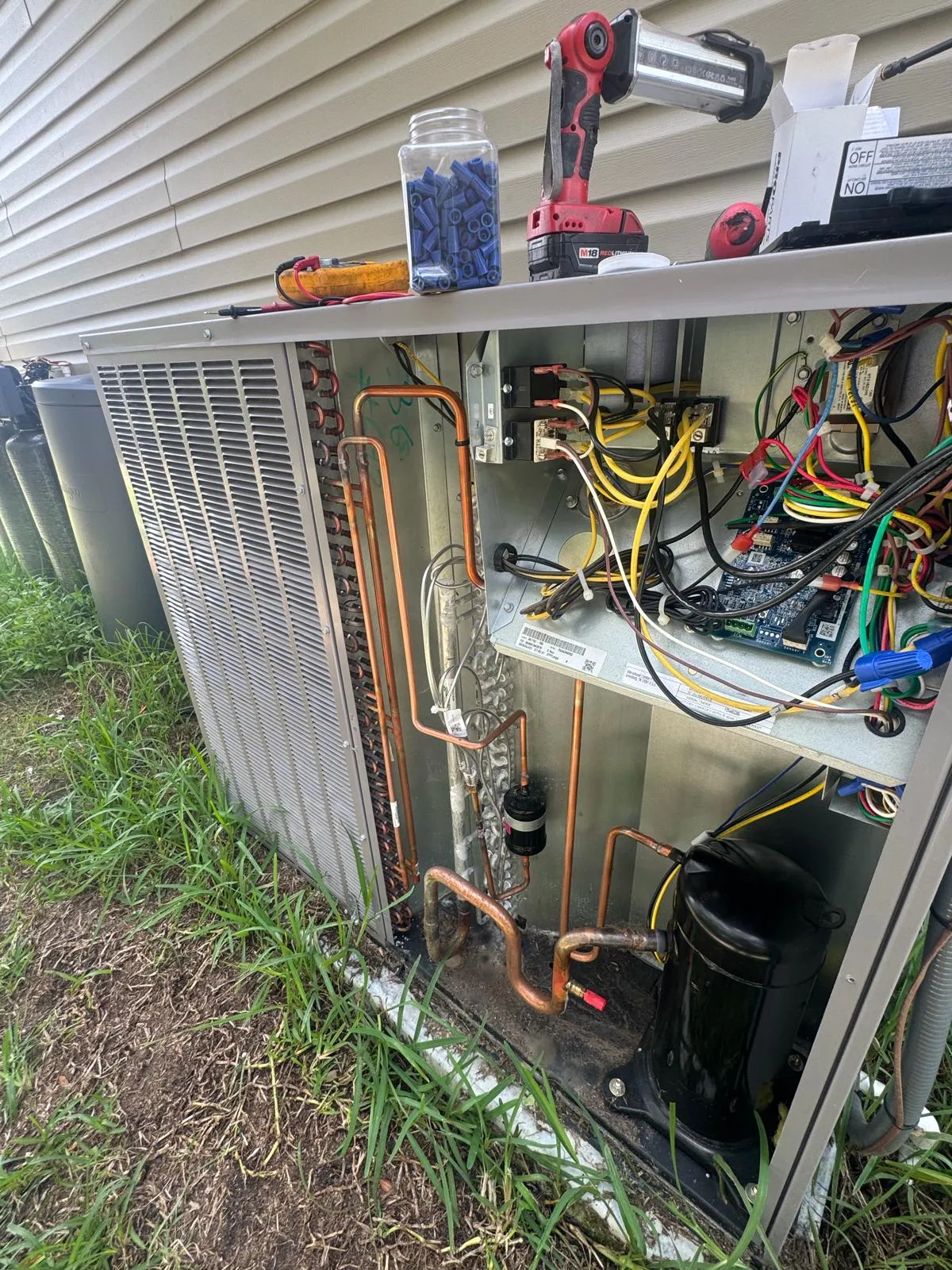 Condenser grille and a multimeter's test leads during an electrical check at a Tampa Bay home